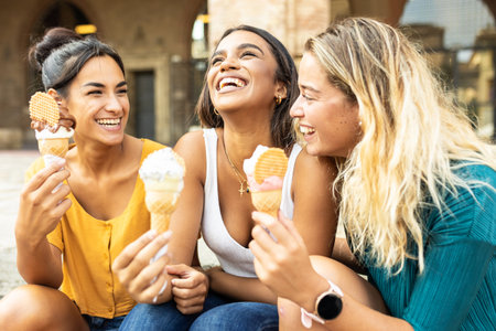 Three cheerful women eating ice cream during summer vacation in Italyの写真素材