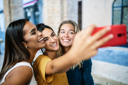 Young happy woman friends of different ethnicities having fun taking selfie
