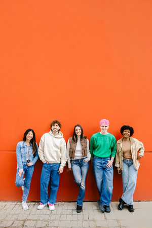Full body portrait of diverse friends standing outdoors against wallの写真素材