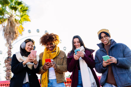 Young group of people in warm clothes using mobile phone device on winter