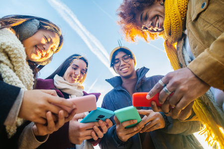Group of young people using smartphones together outdoors in winterの写真素材