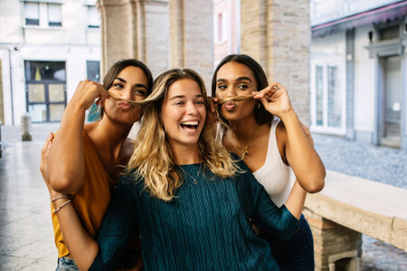 Three happy diverse women enjoying summer vacation taking photo at city street.の写真素材