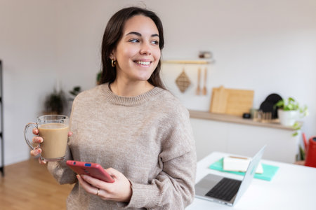 Young happy woman using mobile phone at homeの写真素材