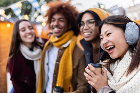Happy multi-ethnic friends enjoying hot drinks at christmas marketの写真素材