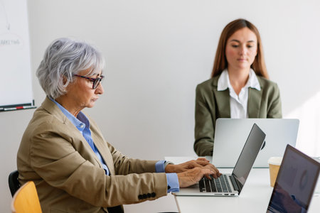 Businesswomen working on laptops in modern office meetingの写真素材