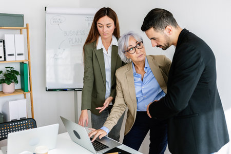 Business team analyzing data on laptop for business plan in officeの写真素材