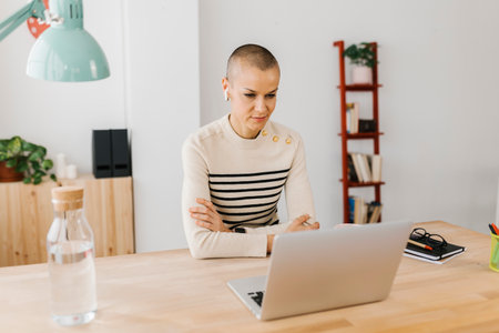 Businesswoman attending video call on laptop sitting at office deskの写真素材