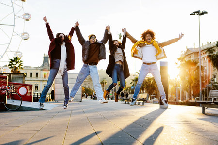 Happy young friends jumping together holding hands in Barcelonaの写真素材