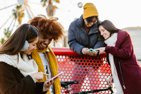 Young group of people in warm clothes using mobile phone device on winterの写真素材