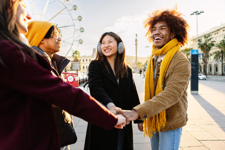 Happy multi-ethnic friends joining hands together in winter holidays at amusement parkの写真素材