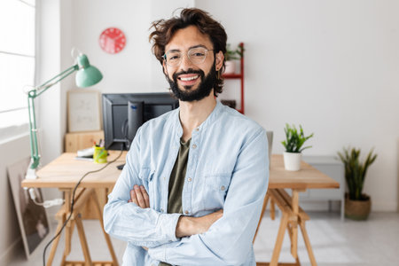 Smiling young creative businessman standing at modern workplaceの写真素材