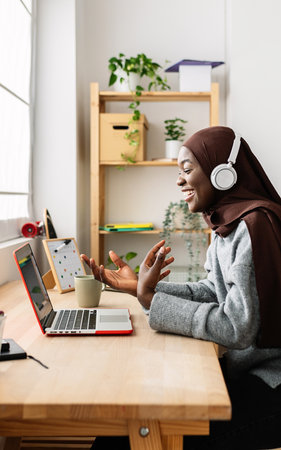 Happy young female student having a video call on laptop at home.の写真素材