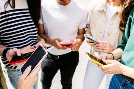 Young group of people using mobile phone app together outsideの写真素材
