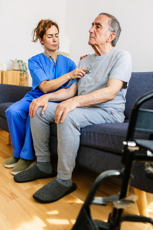 Female doctor listening senior patient heart sound at homeの写真素材