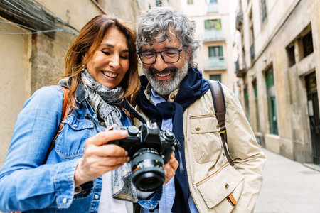 Smiling senior couple reviewing photos on camera in Barcelonaの写真素材