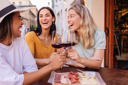 Young women friends laughing with red wine at cafeの写真素材