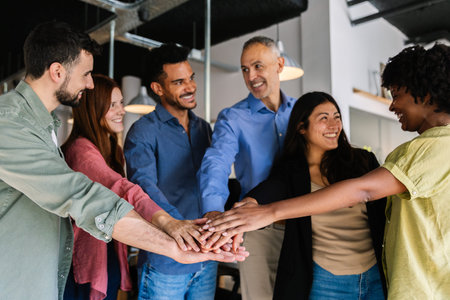 Diverse business team stacking hands showing unity and teamwork