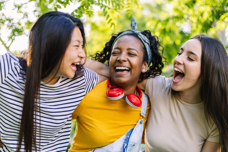 Three young multiracial women laughing together outdoors in summer