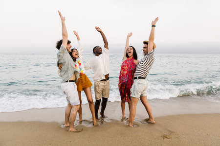 Happy young friends dancing on summer party at beach