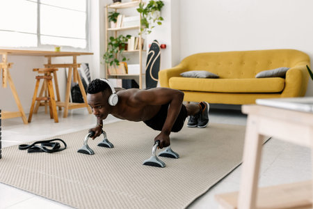 Young adult African athletic man doing push-ups at home