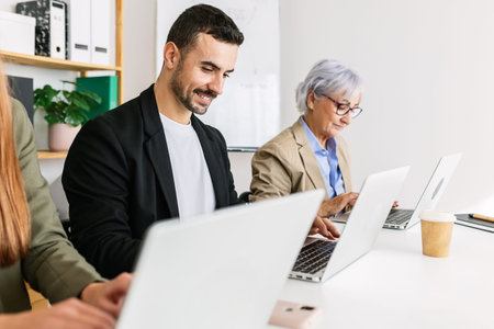 Business team working together on laptops in modern office
