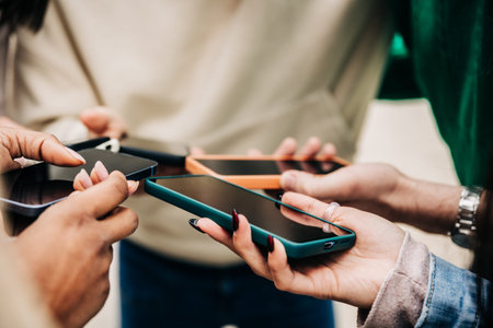 Close up view of teenagers hands using mobile phones outdoors