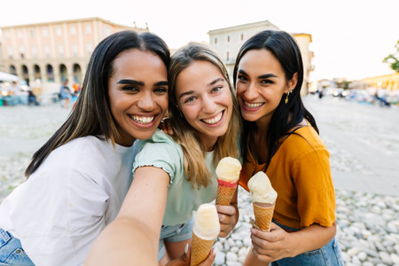 Three female friends eating ice cream while taking selfie during summer vacation