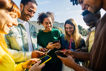 Young group of millennial student friends using mobile phones outdoorsの写真素材