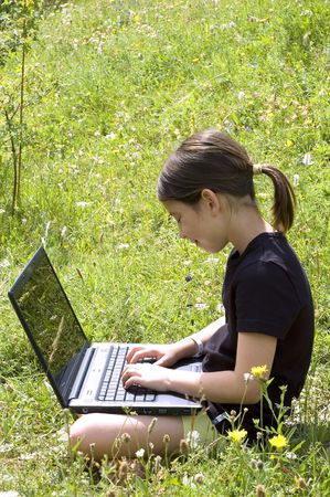 young girl with a laptop in a meadowの写真素材