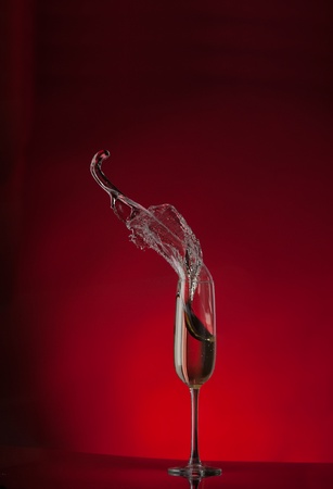 champagne flute splash isolated on red backgroundの写真素材