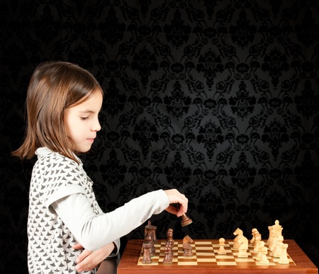 little girl playing chess on vintage backgroundの写真素材