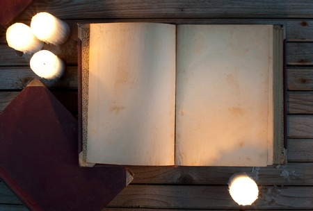 Old opened book and candles on wood backgroundの写真素材