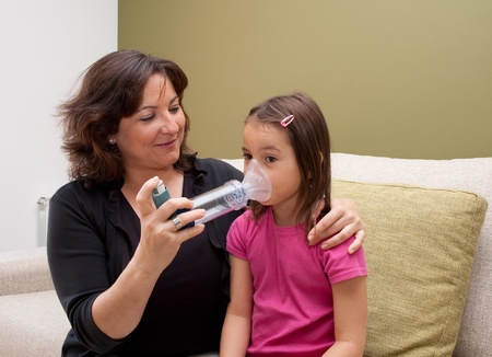 mother using inhaler with her asthmatic daughterの写真素材