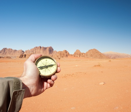 male hand holding compass in the desertの写真素材