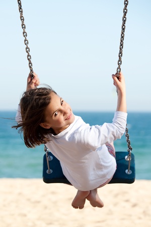 Little girl swinging with the sea in the backgroundの写真素材