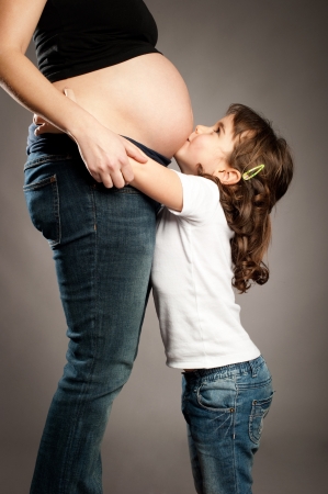 little girl kissing her pregnant motherの写真素材