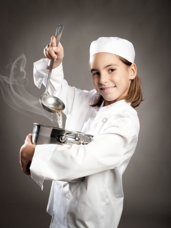 beautiful little chef cooking on gray backgroundの写真素材