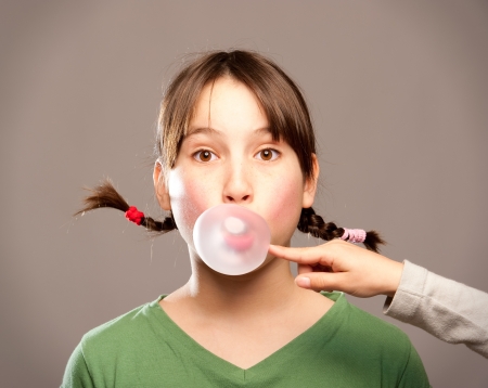 young girl making a bubble from a chewing gum の写真素材