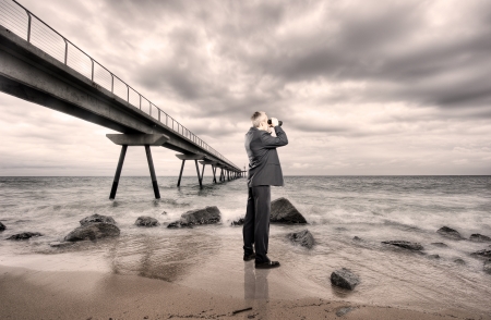 businessman using binoculars on a beachの写真素材