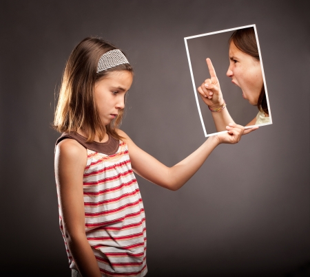 sad little girl  holding a portrait of an angry girlの写真素材
