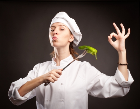 woman chef holding a green pepper with a forkの写真素材