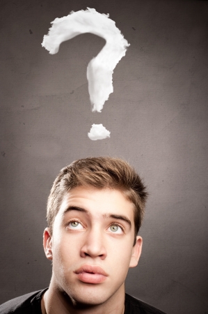 young man thinking with an interrogation symbol over his headの写真素材