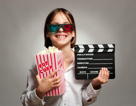 little girl wearing 3D glasses and eating popcornの写真素材