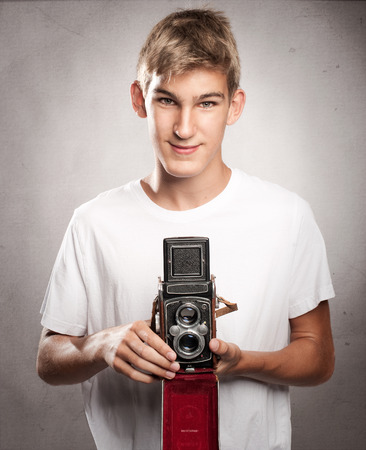young man holding  a vintage camera on a gray backgroundの写真素材