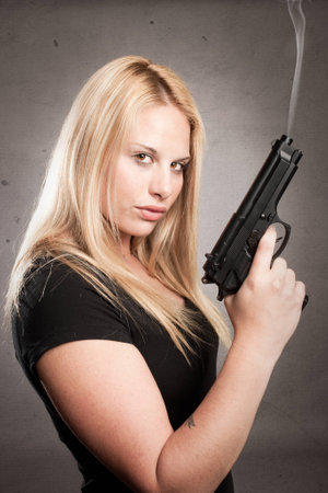 woman with a gun on gray backgroundの写真素材