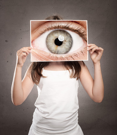 little girl holding a picture of an eye watchingの写真素材