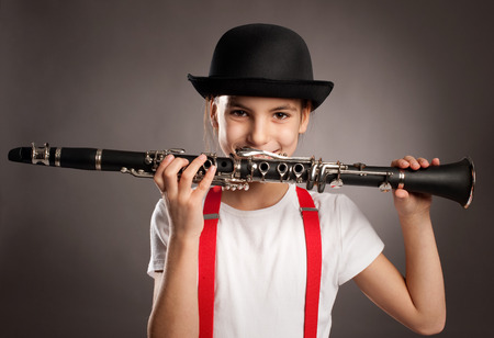 little girl playing clarinet on a gray backgroundの写真素材
