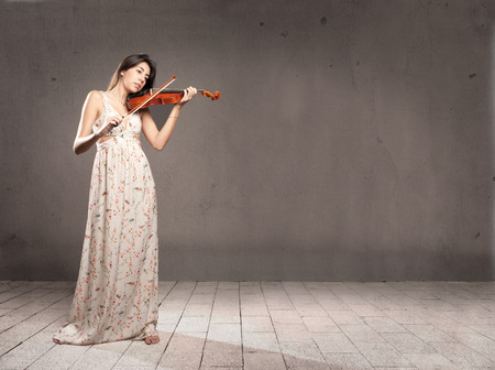 young woman with violin on gray backgroundの写真素材