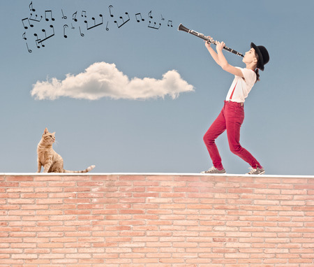 little girl playing clarinet on the top of a bricks wallの写真素材