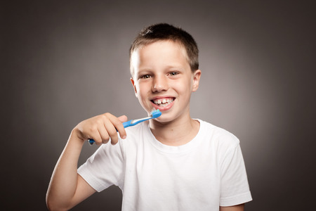 kid brushing his teeth on a gray backgroundの写真素材